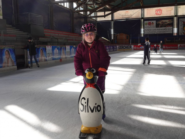 Ein Kind mit einem Pinguin auf dem Eis.